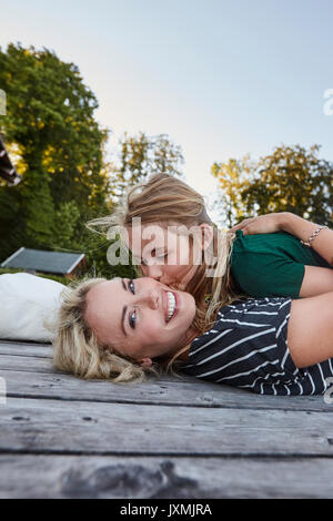 Madre e figlia giacente su legno decking in esterno Foto Stock