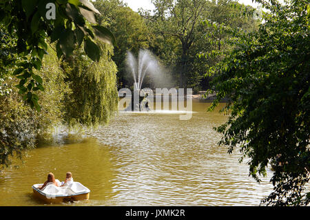 Due giovani ragazze downriver testa sul loro pedalo verso la fontana nel Parco Cismigiu, Bucarest, Romania Foto Stock