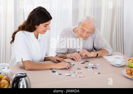 Il sambuco donna giocando Puzzle sul tavolo con la sua balia Foto Stock