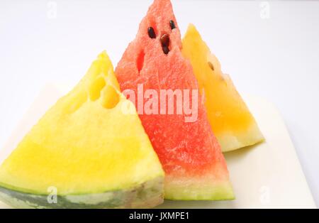 Anguria le fette su piastra bianca. Rosso, arancione e giallo Foto Stock