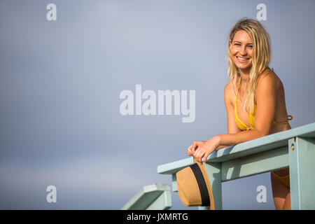 Ritratto di giovane donna in bikini top appoggiata contro il Beach Hut balcone, Santa Monica, California, Stati Uniti d'America Foto Stock