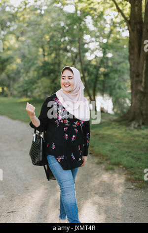 Giovane donna indossa hijab guardando lontano sorridente Foto Stock