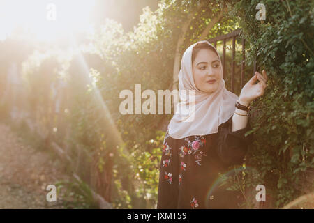 Giovane donna indossa hijab ammirando le piante Foto Stock