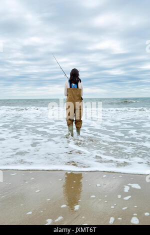 Vista posteriore della giovane donna in waders pesca in mare Foto Stock