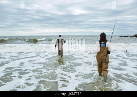 Giovane mare pesca matura in waders, guadare in mare Foto Stock