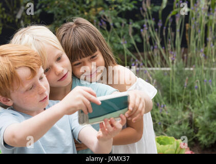 Bambini sorridenti tenendo selfie Foto Stock