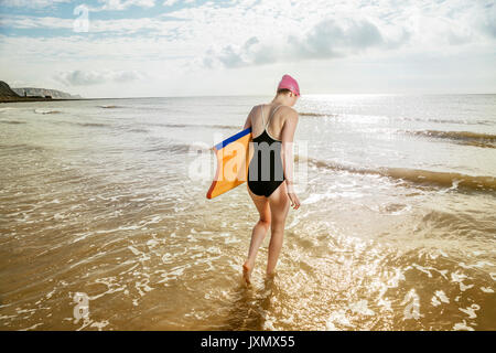 Giovane donna che trasportano le tavole da surf in mare, Folkestone, Regno Unito Foto Stock