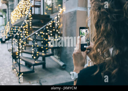 La donna è di scattare le foto della città scenario estivo sul telefono, close-up Foto Stock