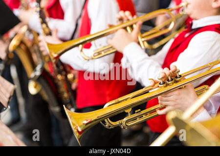 Jazz Band performance concept - orchestra di strumenti a fiato durante lo spettacolo di varietà, il fuoco selettivo sulle mani dei musicisti di suonare alle trombe e sassofoni, closeup maschio rosso in concerto costumi. Foto Stock