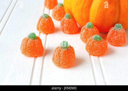 Una miniatura di zucca e zucca jelly candy su un bianco sullo sfondo di legno. Foto Stock