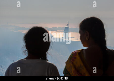 Le donne a guardare il Burj Al Arab hotel contro il tramonto in Emirati Arabi Uniti Foto Stock