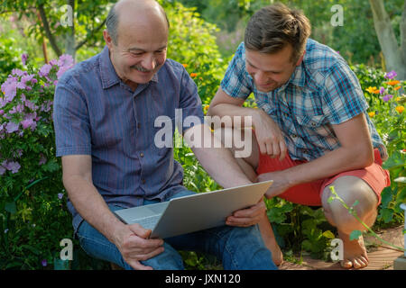 Gli uomini adulti sorridente e cercare qualcosa in internet Foto Stock