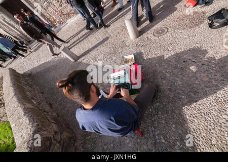 Bohemian scrivere poesie in vecchi nastri inchiostratori per macchine da scrivere sul ponte di Espinosa, Carrera del Darro, Granada, Andalusia, Spagna Foto Stock