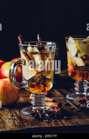 Due bicchieri di Natale vin brulé con fette di mela, chiodo di garofano, cannella, anice Stella e scuro dello zucchero candito. Tutti gli ingredienti e alcuni utensili da cucina su Foto Stock