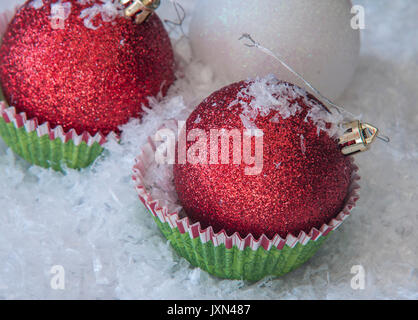 Rosso lucido palle di Natale in stampini per muffin vicino la decorazione di Natale Foto Stock