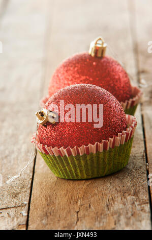 Rosso lucido palle di Natale in stampini per muffin vicino la decorazione di Natale Foto Stock