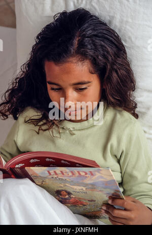 Ragazza giovane 7-10 anni storie di lettura storybook Heidi nel letto americano africano/Caucasian interessati interessanti © Myrleen Pearson Foto Stock