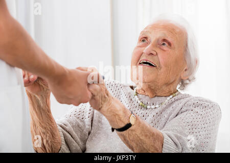 Felice paziente Senior tenendo le mani delle donne medico in ospedale Foto Stock
