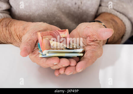 Close-up di Senior di donna che mostra a mano i soldi sul palmare Palm Foto Stock