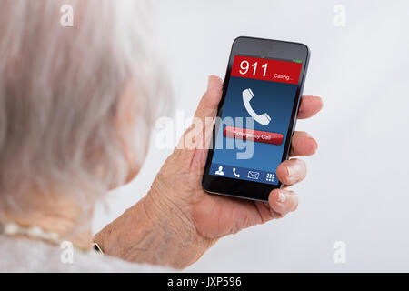 Close-up di Senior composizione donna chiamata di emergenza su Mobilephone a casa Foto Stock