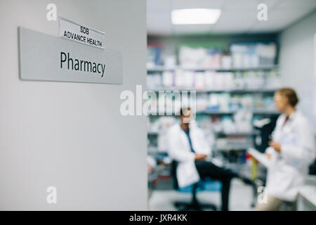 Farmacisti in farmacia dell'ospedale. Focus su farmacia la targhetta sulla porta. Foto Stock