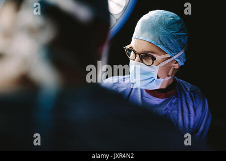 Chirurgo indossando maschera medicale con il team medico di eseguire un intervento chirurgico in ospedale il funzionamento del teatro. Foto Stock