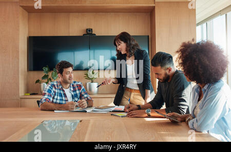 Multirazziale business persone riunite attorno a un tavolo e discutere di nuove strategie. Creativo team di professionisti riuniti nella sala conferenze. Foto Stock