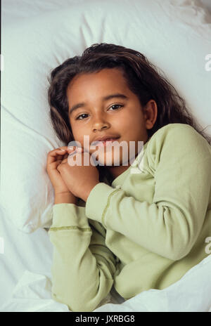 Andare a dormire per la giovane ragazza 7-10 anni in letto pronto a pregare e di andare a dormire African American/Caucasian Foto Stock