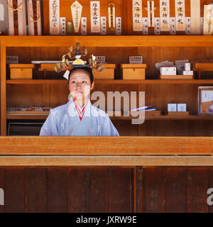 OSAKA, Giappone - 24 ottobre: Santuario aiden di Osaka in Giappone il 24 ottobre 2014. Unidentified 'Miko' a Sumiyoshi Taisha nel contatore vendere wi Foto Stock