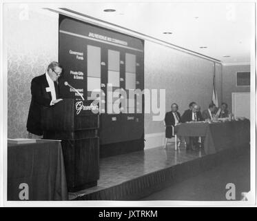 Furlong Baldwin, Campagna per Johns Hopkins Candid Shot, Baldwin guardando in giù a podio, a sinistra del podio è un grafico delle entrate e di un gruppo di uomini non identificati, la Campagna per la Johns Hopkins Evento, 1983. Foto Stock