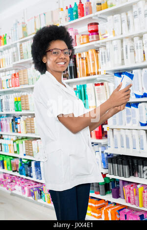 Farmacia femmina tenendo bottiglia di shampoo in farmacia Foto Stock