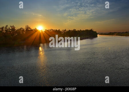 Immagine aerea che mostra un tramonto sull'acqua con raggi solari. bellissimo paesaggio con fiume e luminosi raggi del sole Foto Stock