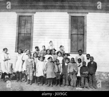 Foto di paesaggio a lunghezza intera di scolari all'aperto, sei studenti afroamericani nel gruppo a destra, 1912. Foto Stock