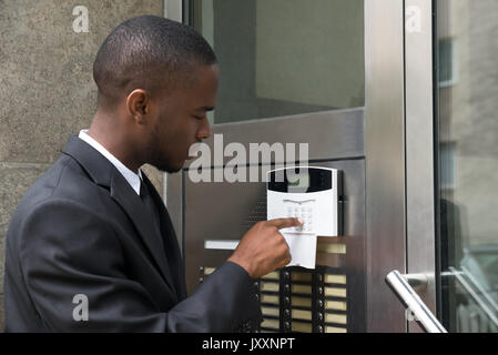 Giovane Imprenditore africano immettendo il codice nel sistema di sicurezza Foto Stock