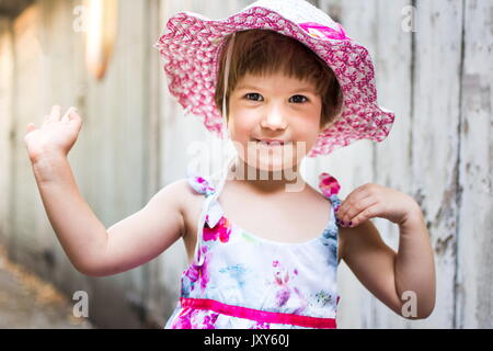 Ragazza carina agitando contro vintage sullo sfondo di legno Foto Stock