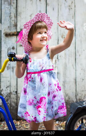 Tre anni ragazza invio saluti con una bicicletta all'aperto Foto Stock