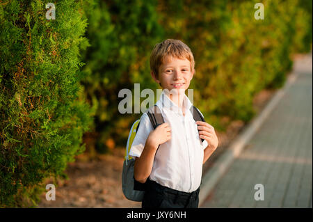 Sorridente scolaro con borsa scuola in esecuzione nella giornata di sole. Ragazzo per andare a casa da scuola. Foto Stock