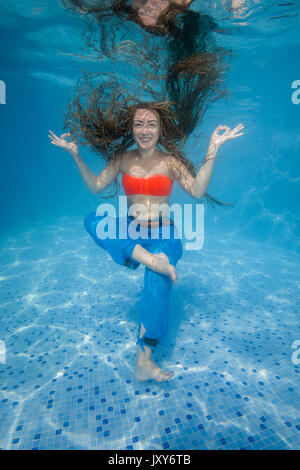 Donna fare yoga sotto l'acqua in piscina Foto Stock