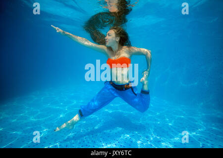 Donna fare yoga sotto l'acqua in piscina Foto Stock