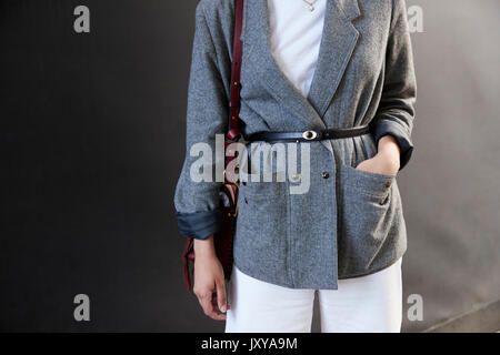 La sezione centrale di una donna in grigio belted giacca e pantaloni bianchi Foto Stock