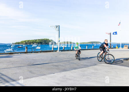 Bar Harbor, Stati Uniti d'America - 8 Giugno 2017: Padre e figlio di andare in bicicletta sul parcheggio del dock con le barche in acqua nel centro di villaggio in estate Foto Stock