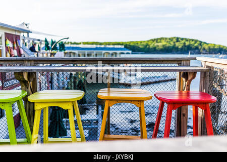 Colorate sedie vivaci dipinte di verde, giallo e arancione sul lungomare con bar e ristorante Foto Stock