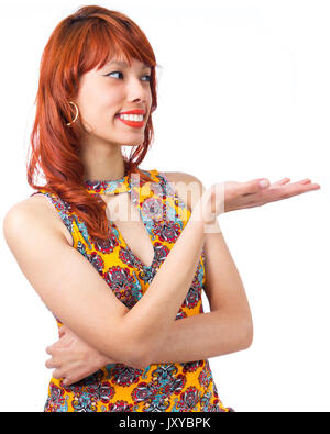 Giovane donna mostra cosa è sul palmo della sua mano. Redhead girl indossa giallo e abiti colorati. Motivo floreale. Moda e stile. Estate e tropi Foto Stock