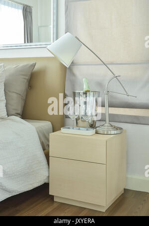 Bianco Lampada da tavolo con bicchieri vuoti e la bottiglia di vino sul comodino Foto Stock