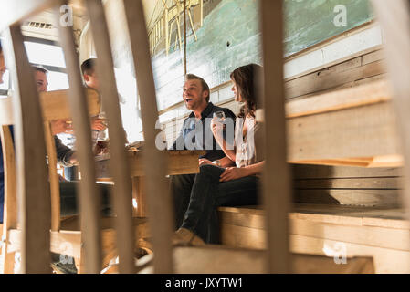 Gli amici di ridere in brew pub dietro la sedia Foto Stock