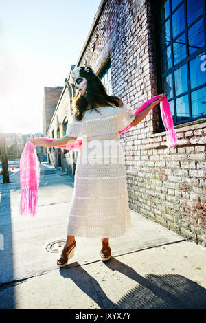 Razza mista woman dancing sul marciapiede che indossa il teschio volto vernice Foto Stock