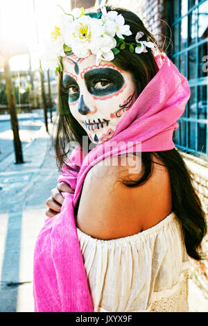 Razza mista donna sul marciapiede che indossa una sciarpa e il cranio face paint Foto Stock