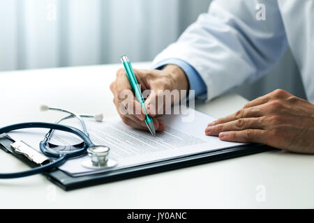 Medico la scrittura di documenti alla scrivania in ufficio cliniche Foto Stock
