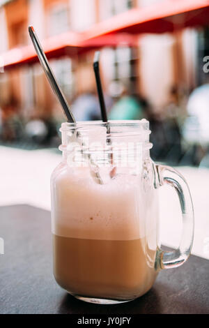 Caffè ghiacciato in un bicchiere mason jar su un tavolo all'aperto. Foto Stock