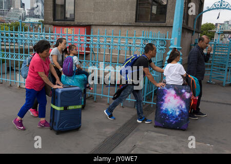 Visitatori cinesi a Londra spingere il loro bagaglio con due bambini Equitazione sulla parte superiore, il 14 agosto 2017, il Tower Bridge di Londra, Inghilterra. Foto Stock